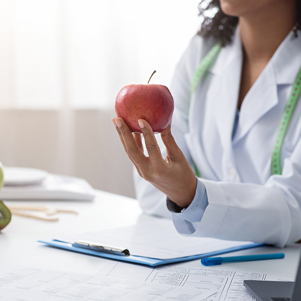 nutritionist holding red apple in front of patient