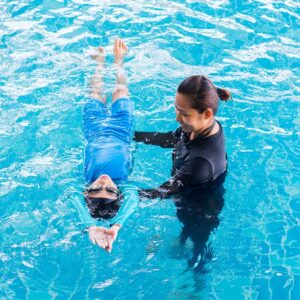 Girl learning to swim with coach